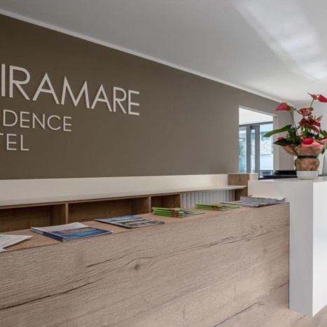 Aparthotel reception. Bancone in laminato rovere con bancalina in full color bianco. 
