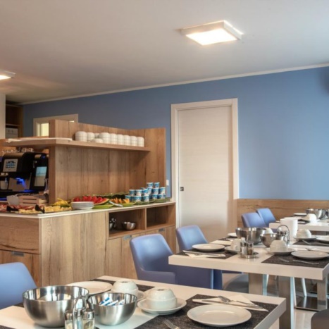Aparthotel sala colazioni. Mobile buffet in rovere. Sedie imbottite similpelle. 