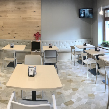 Sala con parete in rovere, tavolini in frassino e sedie in polipropilene 